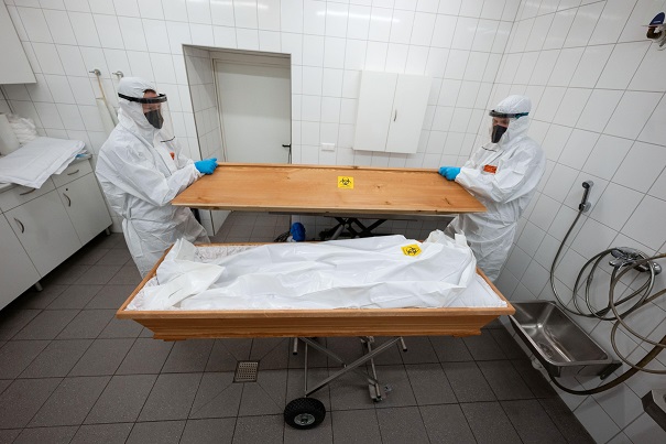2HBPPGA Ulm, Germany. 10th Dec, 2021. Two employees of the First Ulm Funeral Home close the casket of a person who died with Covid-19 and is lying in a body bag. Credit: Marijan Murat/dpa/Alamy Live News